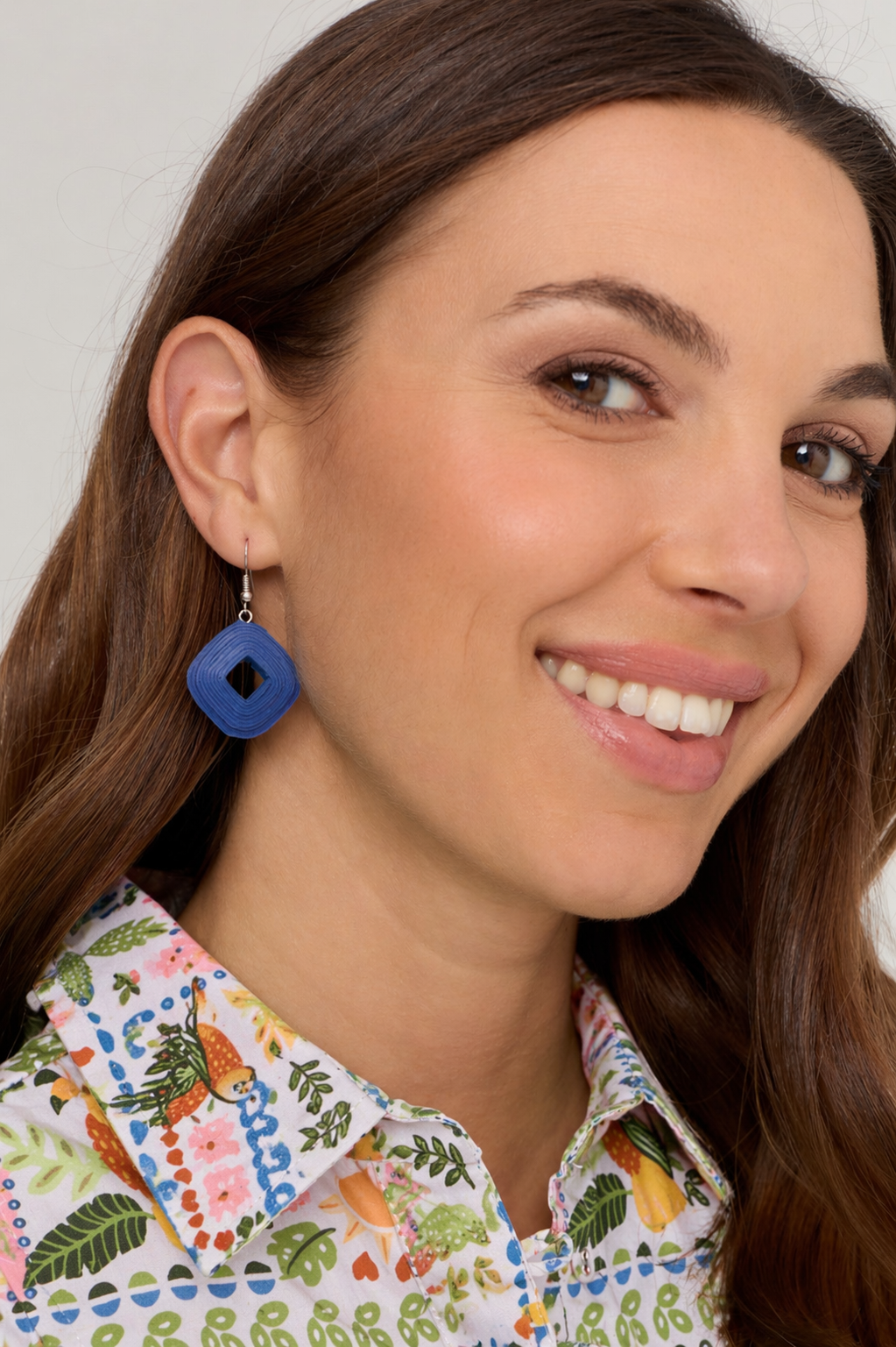 Woman wearing a colorful patterned shirt with a blue earring.